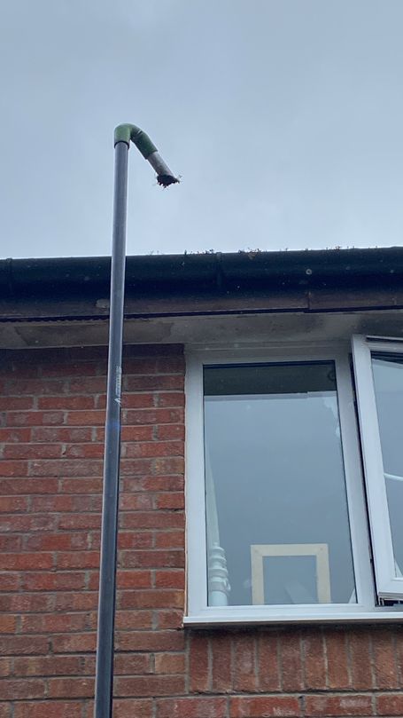 gutter vacuum pole holding debris above gutter on house