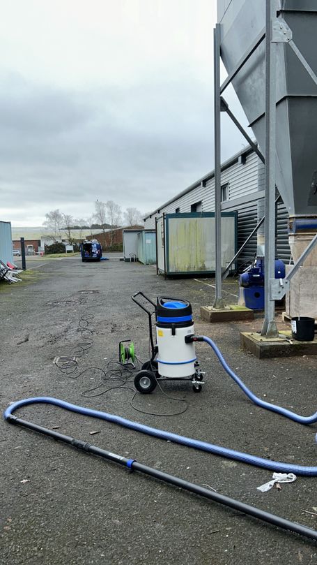 sky vac machine in front of factory, van in distance