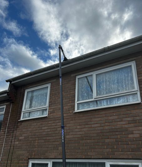 front of house with pole removing debris from gutter